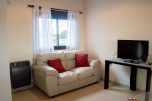 a living room with a white couch and a television at Complejo Moras Departamento Premium con Cama King Centro de Almafuerte in Almafuerte