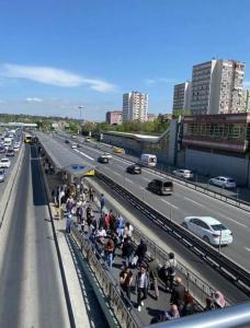 una multitud de personas de pie en un puente al lado de una autopista en Şirinevler Büyük Daire, en Estambul