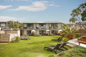 una casa con un patio con sillas y mesas en Beachfront Resort, en Whitianga