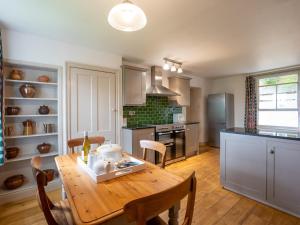 a kitchen with a wooden table and a dining room at The Coach House in Greenhaugh