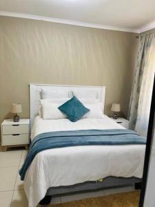 a bedroom with a bed with a blue pillow on it at Central Gabs Oasis: 2BR-Retreat in Gaborone