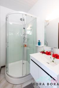 uma casa de banho com uma cabina de duche em vidro e um lavatório. em Matira Beach Raitea 2 em Bora Bora