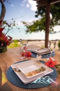 einen Tisch mit Teller und Gläsern auf dem Tisch in der Unterkunft Matira Beach Raitea 2 in Bora Bora