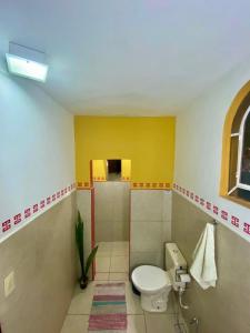 łazienka z toaletą i żółtą ścianą w obiekcie HOSTEL Divinópolis w mieście Divinópolis