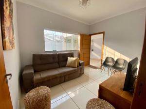 uma sala de estar com um sofá e cadeiras castanhos em Casa no Centro da Cidade/Com ar condicionado em Marília
