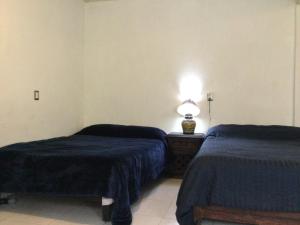 a room with two beds and a lamp on a table at Trotamundo Oaxaca Hostel in Oaxaca City