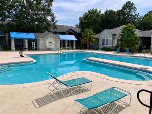 a large swimming pool with two chairs in front of a house at Stylish Serenity: Your Central Peace Zone! in Gainesville