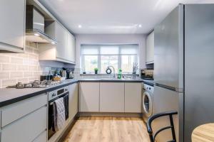 a kitchen with white cabinets and a sink and a dishwasher at Stunning Designer House with Parking Sleeps 8 by PureStay Short Lets & Serviced Accommodation Liverpool in Litherland
