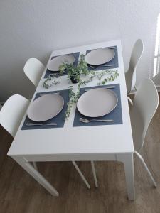 a white table with white chairs and plates and flowers at Eine schöne Wohnung im Herzen von Bremerhaven in Bremerhaven