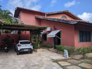 um carro estacionado em frente a uma casa vermelha em BH Studio Casa grande em Fortaleza em Fortaleza