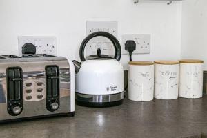 a counter with a toaster and three cups on it at Luxury 2 Bedroom 2 Bathroom Apartment - City Centre - Free Parking, Balcony and Smart TVs with Sky TV and Netflix by Yoko Property in Milton Keynes