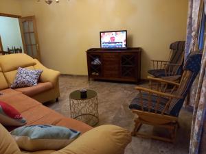 a living room with a couch and a tv at Alojamiento Vacacional Inma in Cazorla