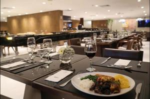 uma mesa com um prato de comida e copos de vinho em Flat no Hotel Radisson em Belém