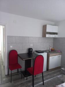 uma pequena cozinha com duas cadeiras vermelhas e uma mesa em Adagio Studio Apartment em Plav
