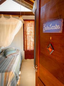 a bedroom with a bed and a door with a sign at CASA Ecológica Paraty in Paraty