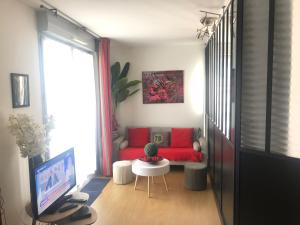 Una sala de estar con un sofá rojo y un televisor. en Le Petit Zénith, en Saint-Herblain