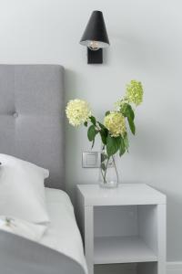 a vase with flowers on a night stand next to a bed at Apartament Doris 1 z pięknym widokiem in Pobierowo