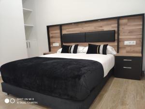 sypialnia z dużym łóżkiem z czarnym kocem w obiekcie Apartamentos Silgar Plaza w mieście Sanxenxo