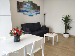 a living room with a white table and a black couch at Apartamentos Silgar Plaza in Sanxenxo