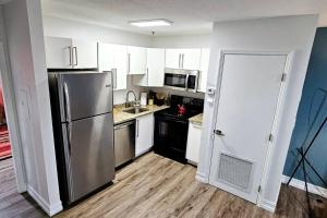 a kitchen with white cabinets and a stainless steel refrigerator at The Lofts on Clematis 204 Downtown West Palm Beach in West Palm Beach