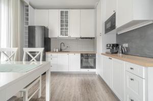 a white kitchen with white cabinets and a table at Apartament Doris 1 z pięknym widokiem in Pobierowo