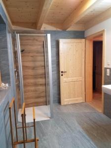 a bathroom with a wooden door and a chair at Almhütte mit Sonnenterrasse - Holzofen - Sauna in Bad Sankt Leonhard im Lavanttal