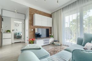 a living room with a blue couch and a television at Apartament Doris 1 z pięknym widokiem in Pobierowo
