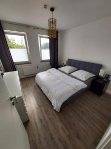 a bedroom with a large bed and two windows at Seibels SUITES - Wohnung Ruhrgebiet in Herne