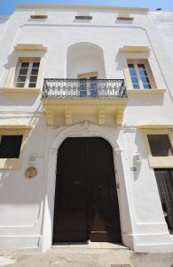 un edificio blanco con puerta negra y balcón en Palazzo Zacà, en Gallipoli