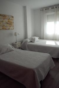 a bedroom with two beds and a window with at Edificio La Isla in Puerto de Mazarrón