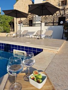 tavolo con bicchieri da vino e cesto di frutta accanto alla piscina di Villa Penelope a Douliana