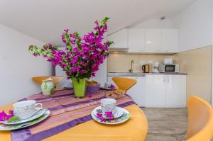 una mesa de comedor con flores púrpuras en la cocina en Apartment Karolina, en Poljica