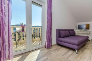 sala de estar con silla púrpura y balcón en Apartment Karolina, en Poljica