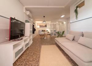 sala de estar con sofá blanco y TV de pantalla plana en La casita de la tortuga, en Melenara