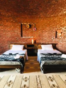 2 camas en una habitación con una pared de ladrillo en Gazrashek, en ‘Izbat Ţanāţī