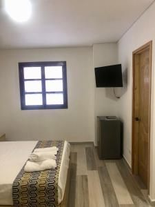 1 dormitorio con 1 cama, TV y ventana en ALTO VERDE HOTEL, en Guatapé