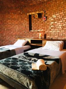 2 camas en una habitación con una pared de ladrillo en Gazrashek, en ‘Izbat Ţanāţī