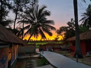 einen Sonnenuntergang über einem Resort mit einer Palme in der Unterkunft CAMPAMENTO CHEZ CAMPOS in Cap Skirring