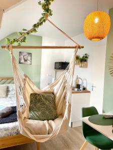 a hanging hammock chair in a room with a bed at Le studio d'Angèle : KIMI in Bruz