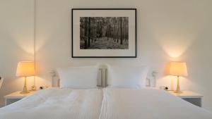 a bedroom with a white bed with two lamps at nook Lakehouse in Bad Saarow