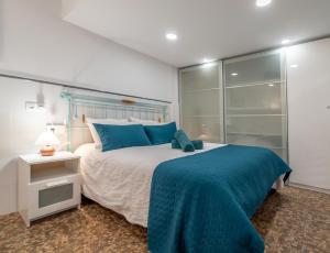 1 dormitorio con 1 cama grande con almohadas azules en La casita de la tortuga, en Melenara