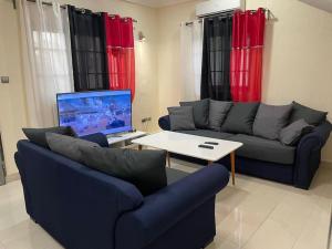 uma sala de estar com um sofá, uma mesa e uma televisão em Villa toute équipée à Arconville em Abomey-Calavi
