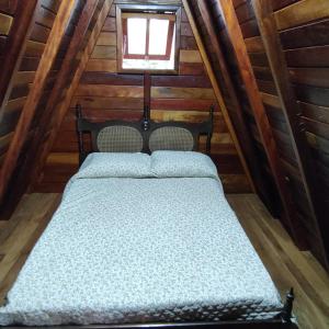 a bed in the attic of a log cabin at Chalé Europeu na Beira do Rio in Pederneiras