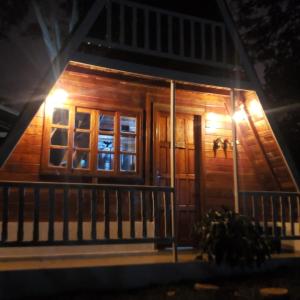a wooden cabin with a porch at night at Chalé Europeu na Beira do Rio in Pederneiras