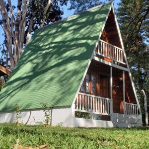 a small house with a green roof at Chalé Europeu na Beira do Rio in Pederneiras