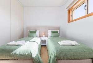 2 camas en una habitación con sábanas verdes y una ventana en A Casa da Bela Vista, en Albergaria-a-Velha