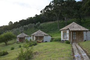 Deux petites cabanes sur une colline herbeuse avec des arbres dans l'établissement Espaço Lua Branca, à Baependi