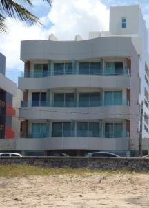 - un bâtiment sur la plage avec des voitures garées devant dans l'établissement Flat Beira Mar Terrazzas, à João Pessoa