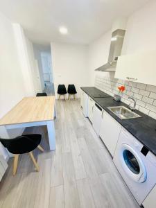 uma cozinha com um lavatório, uma mesa e cadeiras em Apartamentos Rurales La Plaza 1 em Duruelo de la Sierra