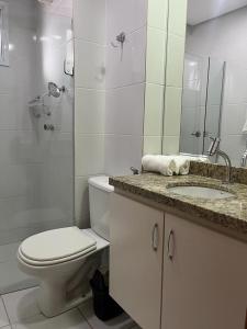 y baño con aseo, lavabo y espejo. en Excelente Apto setor Bueno 1101, en Goiânia